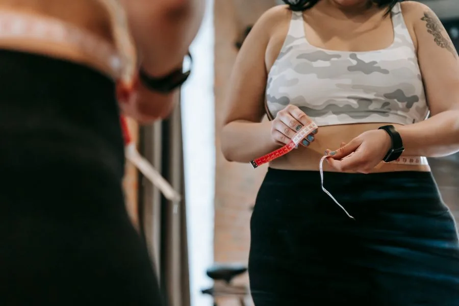 Woman measuring her waist with a tape measure