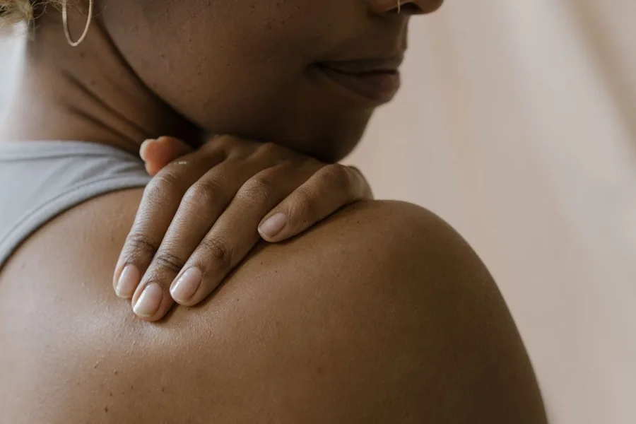 Woman gently touching her bare shoulder